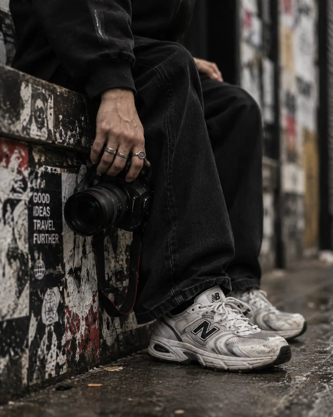 Photographer seated beside a wall of layered street posters